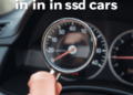 Close-up of a car dashboard with a hand holding a magnifying glass over the odometer, highlighting scrutiny of odometer readings.