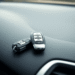 Close-up of a shiny car key fob on a smooth dashboard with a blurred sleek vehicle reflection in soft natural light.
