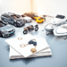 A bright, modern scene with a car, SUV, motorcycle, and boat parked neatly beside documents with seals and keys, symbolizing organized vehicle tran...